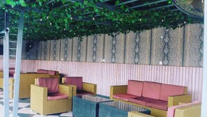 A covered outdoor seating area with wicker furniture and a checkered floor. - Clase Alta Hotel and Suites Limited (Benin City)