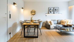 A modern living room with a dining area, featuring a sofa, a coffee table, and a dining table set for four. - Nova 1-Bedroom Apartment in Athens (Greece - Athens)