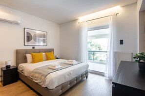 Un dormitorio moderno con una cama grande, una mesita de noche, una planta en maceta y vistas al exterior.
