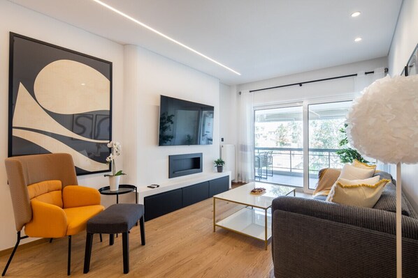 Una sala de estar moderna con un sofá, un sillón, una mesa de centro y un televisor montado en la pared.
