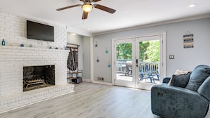 Un salon doté d’une cheminée, d’un ventilateur de plafond et d’une porte-fenêtre coulissante donnant sur un espace extérieur.