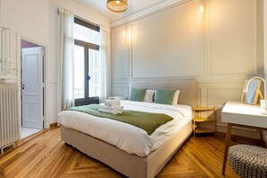 Une chambre d’hôtel bien aménagée, avec un grand lit, une table de chevet, une chaise et une fenêtre avec des rideaux.