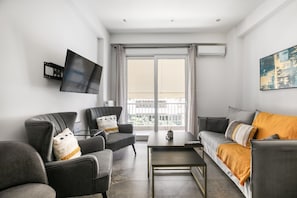 Una sala de estar moderna con sofá, sillones, una mesa de centro y un televisor de pantalla plana montado en la pared.
