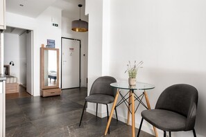 Una habitación moderna con una mesa de vidrio, dos sillas, un espejo y una puerta que da a otra habitación.