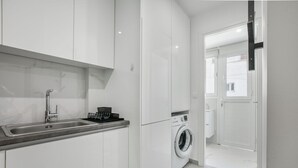 A modern kitchen with a built-in sink, a washing machine, and a door leading to another room. - Mellow 2-Bedroom Apartment in Athens (Greece - Athens)