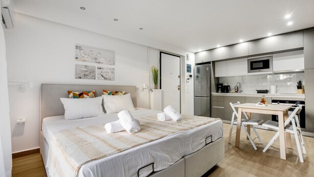Une chambre d’hôtel moderne avec un grand lit, une petite table à manger et un coin cuisine.