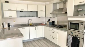 Eine moderne Küche mit weißen Schränken, einer Edelstahl-Dunstabzugshaube, einer Mikrowelle und einem Backofen.