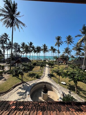 Un resort tropical con palmeras, un camino de piedra y vista al océano.