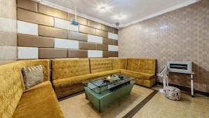 Una sala de estar con un sofá modular, una mesa de centro de vidrio y un equipo de aire acondicionado instalado en la pared.