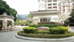 Un edificio con un patio central, rodeado de vegetación y un monumento de piedra.