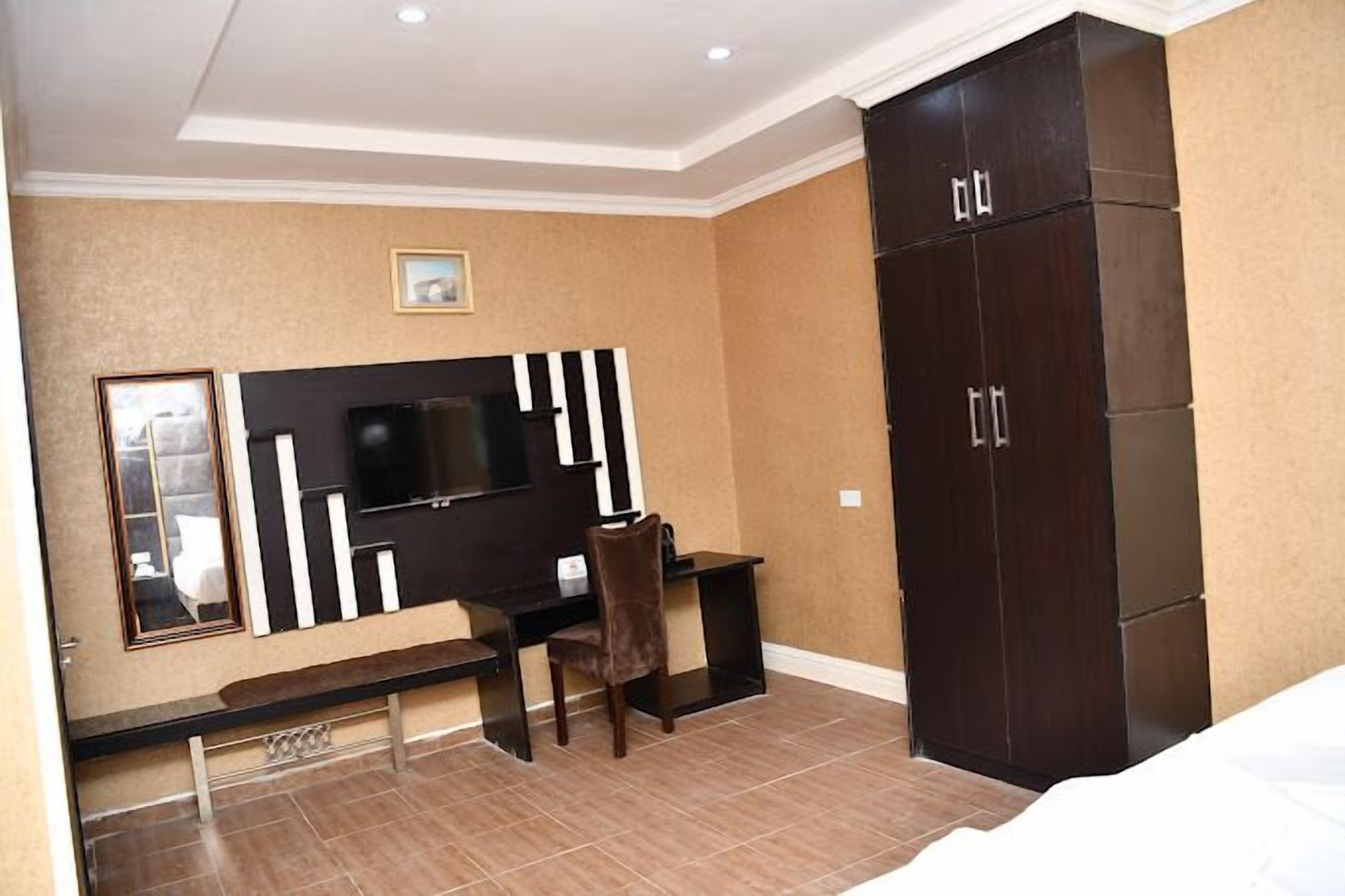 Un dormitorio con cama, escritorio, silla, armario y televisor.