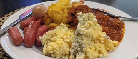 A plate with sausages, potatoes, scrambled eggs, and a tomato-based dish.
