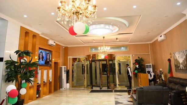 A lobby with a chandelier, a reception desk, a television, and a seating area. - View point Hotel and Suites  (Benin City)