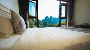A bed with a mountain view through large windows. - Zhangjiajie Xianlv Residential Accommodation (Wulingyuan National Scenic Spot Scenic Spot Store) (Zhangjiajie)