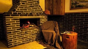 A brick fireplace with a fire, a wooden cabinet, and a small wooden stool with a glass of wine. - Zhangjiajie Xianlv Residential Accommodation (Wulingyuan National Scenic Spot Scenic Spot Store) (Zhangjiajie)