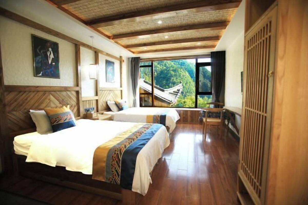 Habitación con dos camas, piso de madera, vista a un puente tradicional y un ventanal grande.