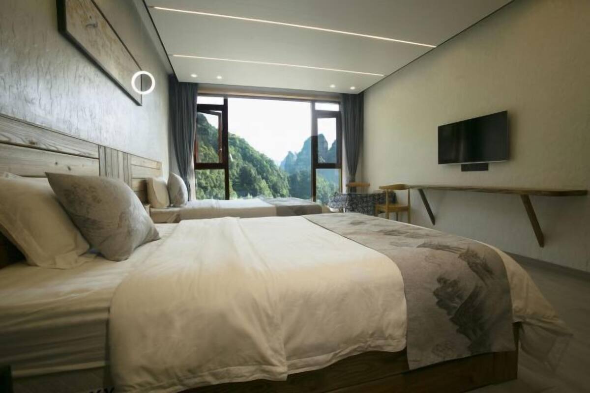 Un dormitorio con una cama grande, televisión y vistas a las montañas.