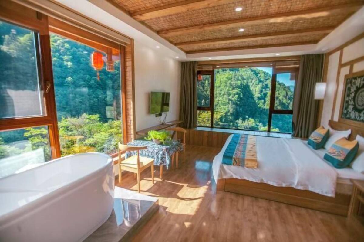 Un dormitorio con una ventana grande, una bañera, una cama y una pequeña mesa con sillas.