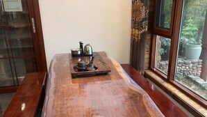 A wooden table with a tray and tea set, positioned near a window with a view of greenery and a stone structure. - Zhangjiajie Xianlv Residential Accommodation (Wulingyuan National Scenic Spot Scenic Spot Store) (Zhangjiajie)