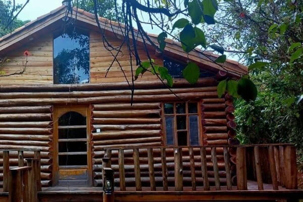 Una cabaña rústica de madera con un porche y una puerta principal pequeña.
