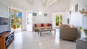 A spacious living room with a large TV, two sofas, a coffee table, and a TV stand.