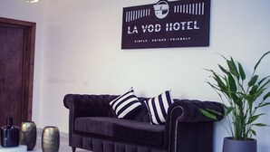 A modern hotel interior with a dark-colored sofa, striped pillows, and a potted plant. - La VOD Hotel (Benin City)