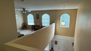Ein geräumiges Zimmer mit hoher Decke, einem Deckenventilator und einem Essbereich mit Tisch und Stühlen.