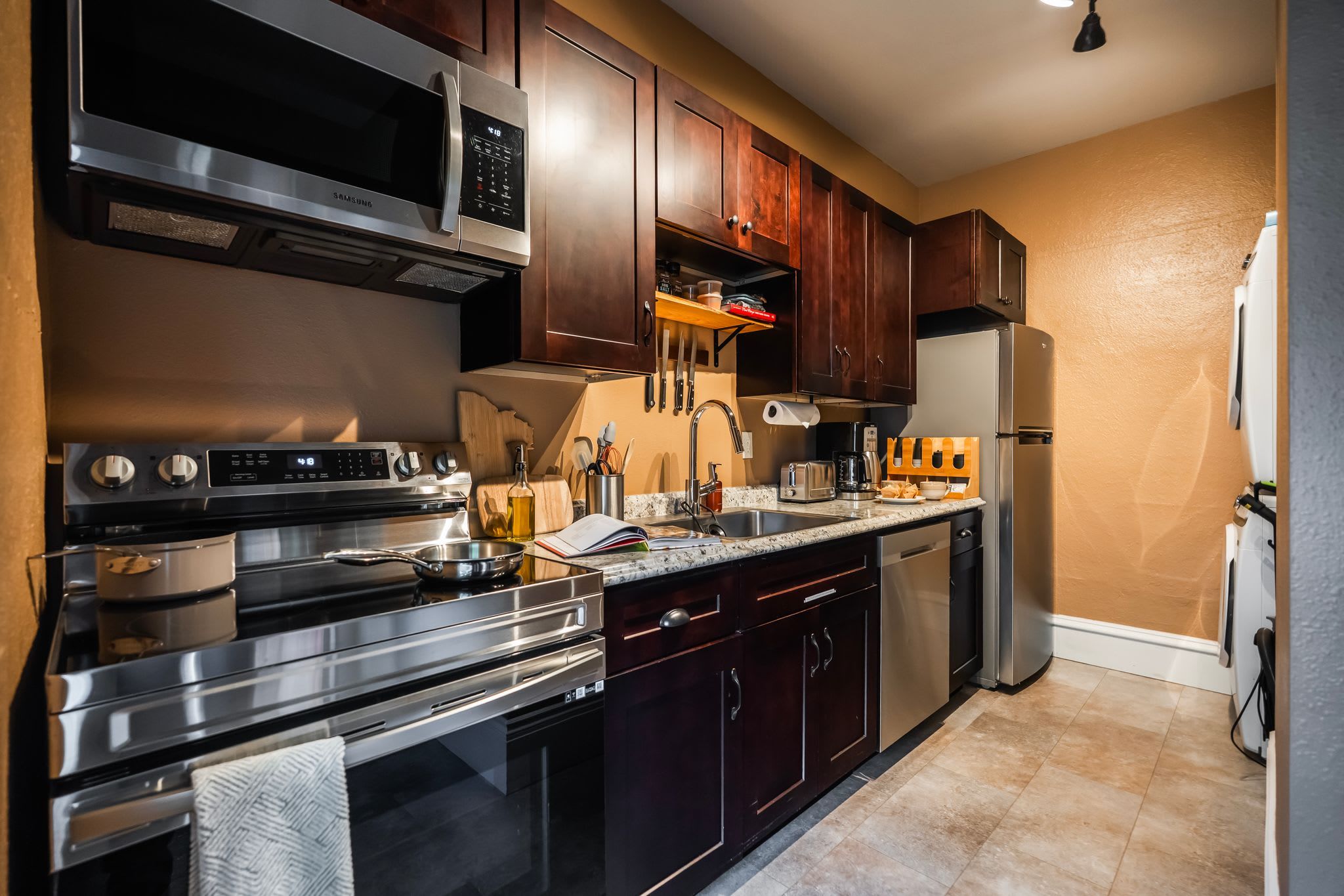 A modern kitchen with stainless steel appliances, wooden cabinets, and a granite countertop.