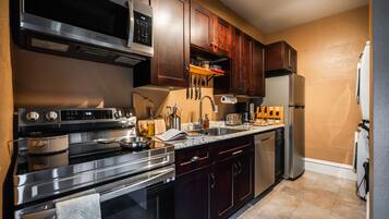 A modern kitchen with stainless steel appliances, wooden cabinets, and a granite countertop.