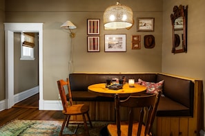 Una habitación acogedora con un banco de madera, una mesa redonda y una lámpara colgante.