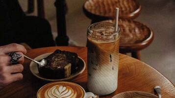 A table with a cup of coffee, a glass of iced coffee, a plate with a cookie, and a plate with a dessert.
