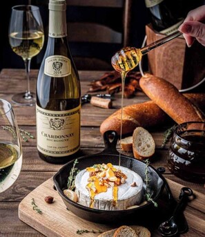 A bottle of Louis Jadot 2018 Chardonnay, a charcuterie board with bread, and a dish of cheese with honey and nuts. - Couples Retreat: King+ Sauna + HotTub I Downtown (Sandpoint)