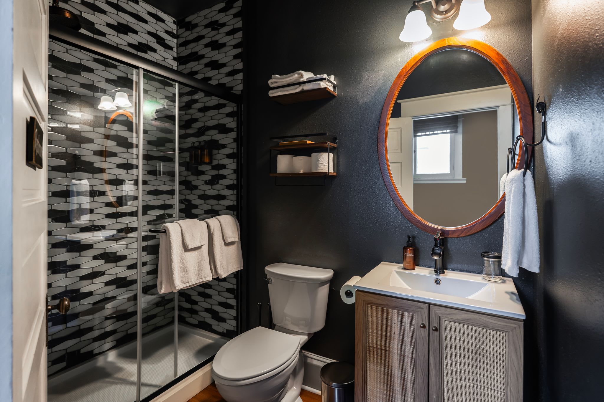 A modern bathroom with a glass shower enclosure, a toilet, a sink with a mirror, and a towel rack.