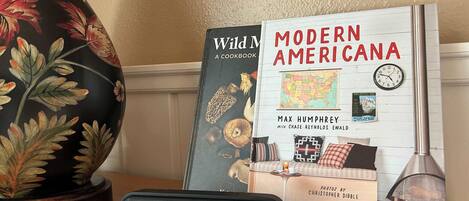 En bog med titlen 'Modern Americana' af Max Humphrey, der viser et kort over USA på omslaget, en dekorativ vase og en moderne højttaler på et træbord.