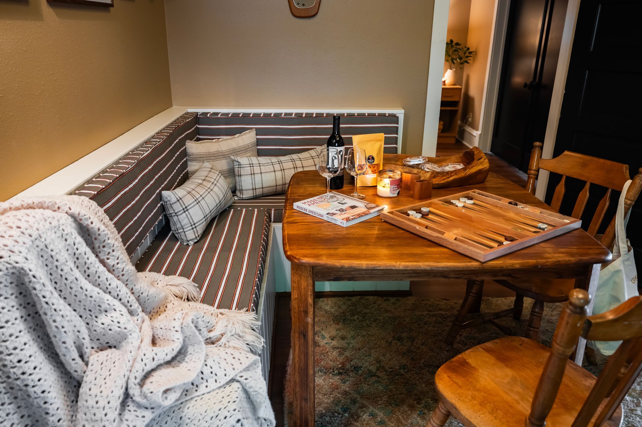 A cozy seating area with a bench, a table with a board game, and a candle.