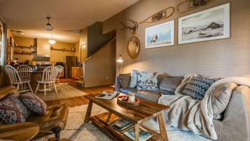 A cozy living room with a sofa, coffee table, and a dining area with chairs.