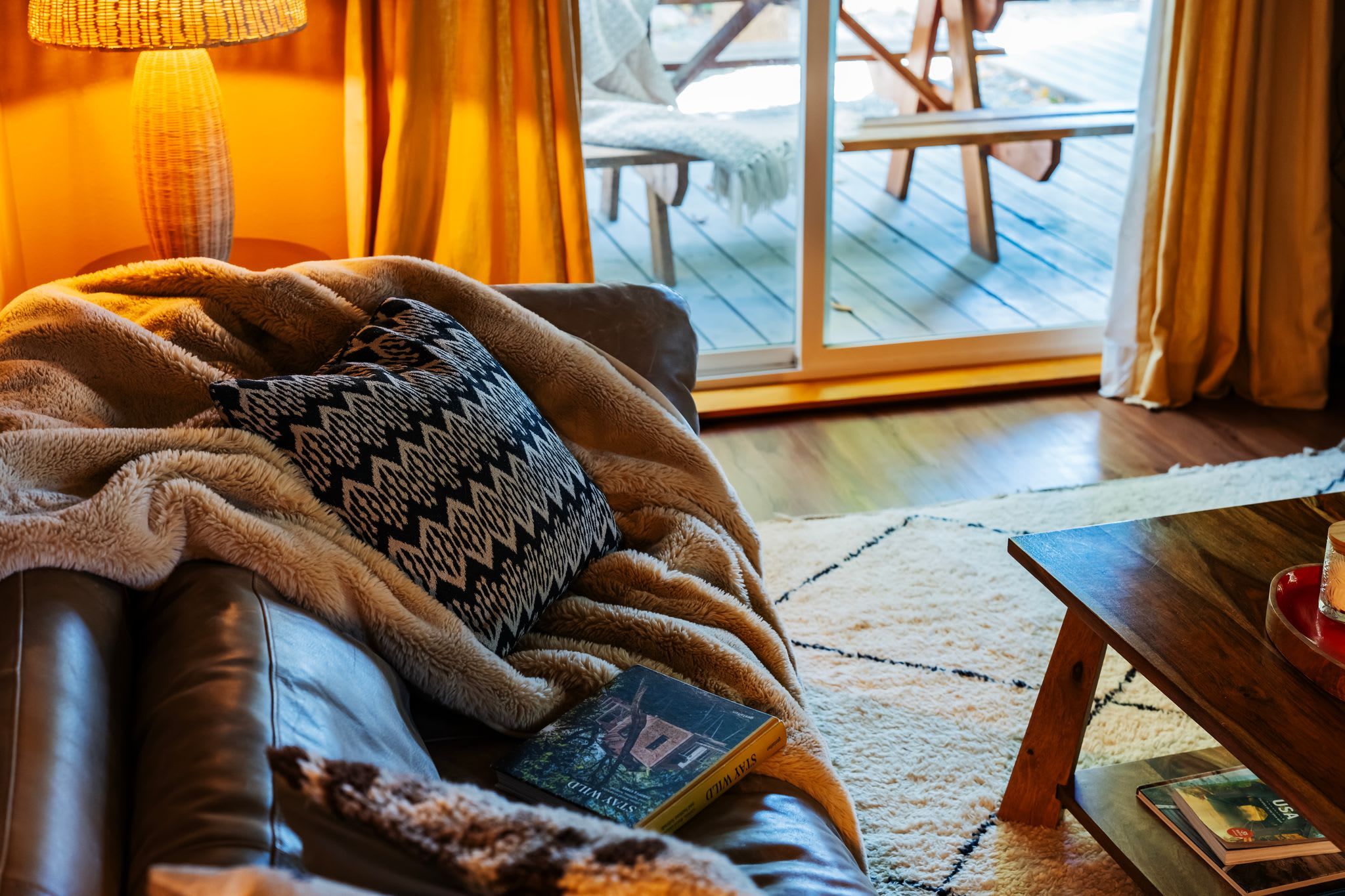 Een gezellige woonkamer met een leren bank, een geborduurde plaid en een boek.