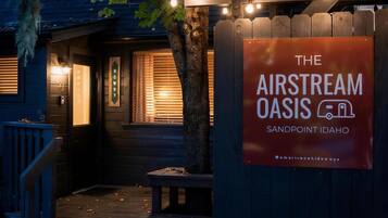 A wooden cabin with a sign for 'The Airstream Oasis' in Sandpoint, Idaho.