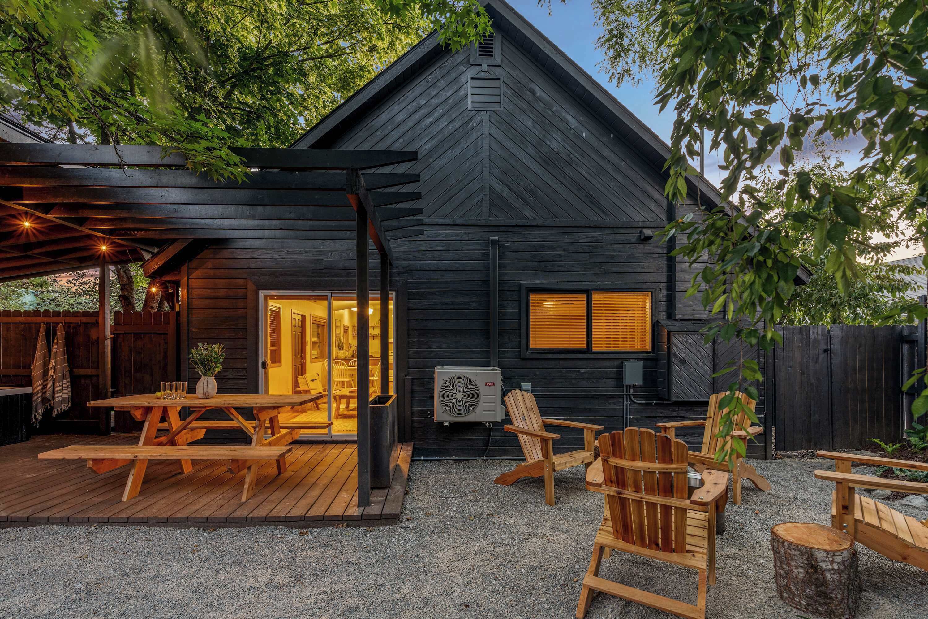 A cabin with a deck, outdoor seating, and an air conditioning unit.