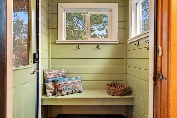 A small, green-walled room with a bench, two pillows, and a wicker basket. - Cozy Airstream Sauna + Hot Tub | Sleeps 4 Downtown (Sandpoint)