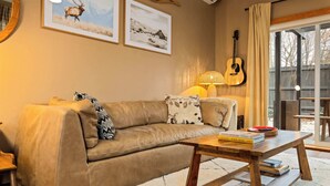 Een gezellige woonkamer met een leren bank, een houten salontafel en een gitaar die tegen de muur staat.