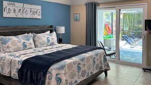 Ein Schlafzimmer mit Bett, Deckenventilator, Wanduhr und Blick ins Freie.