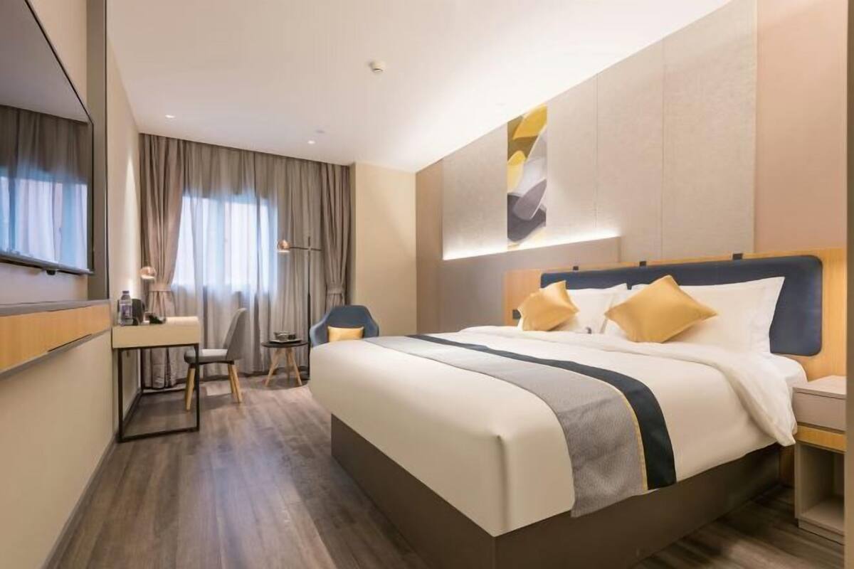 A modern hotel room with a large bed, a desk, and a chair.