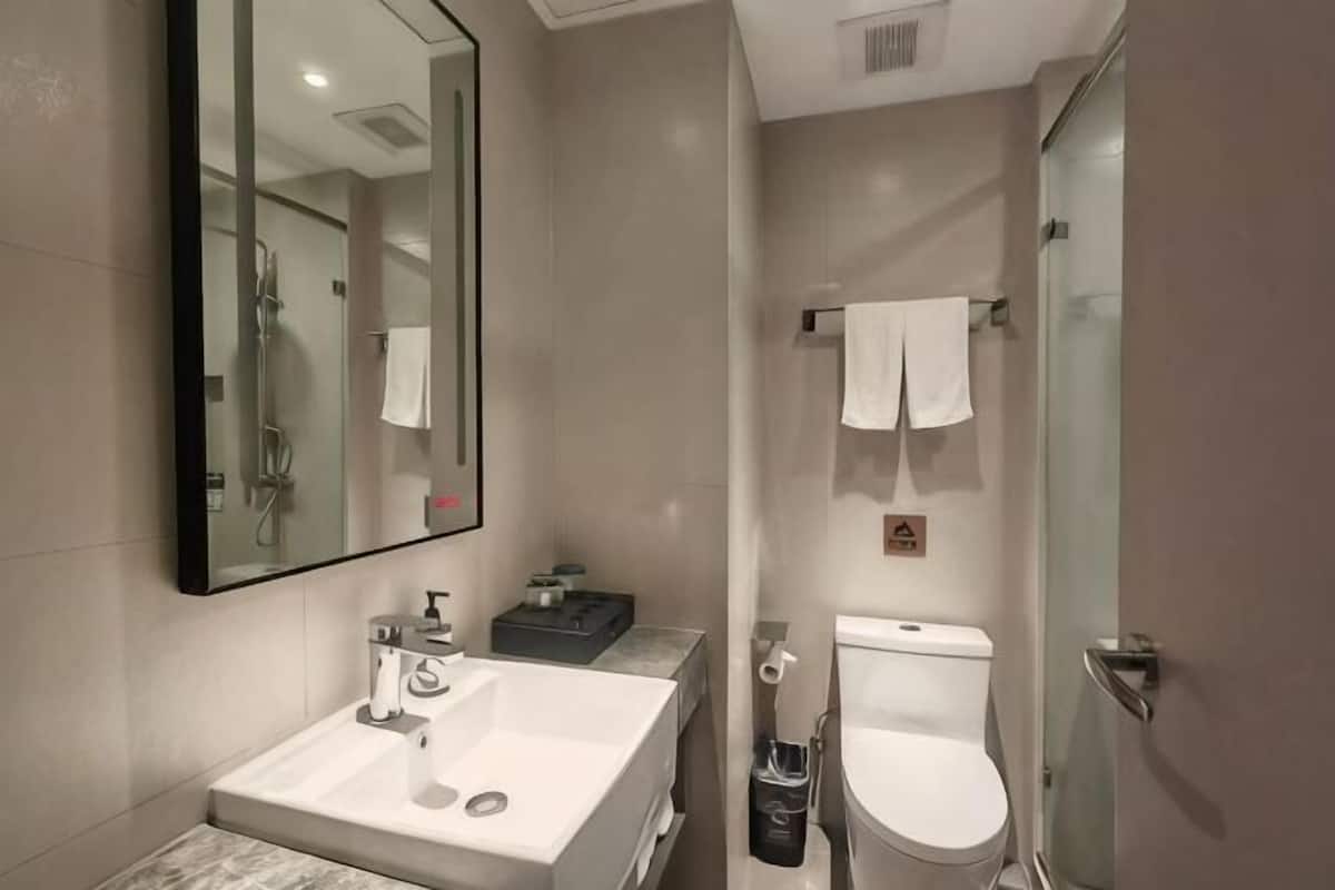 A modern bathroom with a sink, mirror, toilet, and shower.