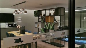 Un hall d’hôtel moderne comprenant un comptoir d’accueil, un espace repas avec une table et des chaises, ainsi qu’une bibliothèque agrémentée d’objets décoratifs.