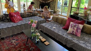A cozy living room with patterned sofas, a fireplace, and a large window offering a view of greenery outside. - The Race Mountain House (Sheffield)