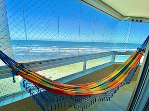A hammock on a balcony with a view of the ocean. - Edifício Breno Navarro  (Praia Grande)