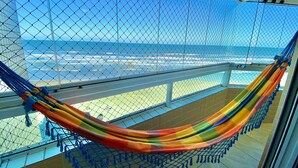 A hammock on a balcony with a view of the ocean. - Edifício Breno Navarro  (Praia Grande)