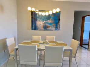 Un espace repas comprenant une table, des chaises et un luminaire fixé au mur.