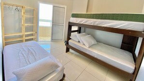 Un letto a castello con una testiera verde, un armadio in legno e una porta scorrevole in vetro che dà su un balcone.